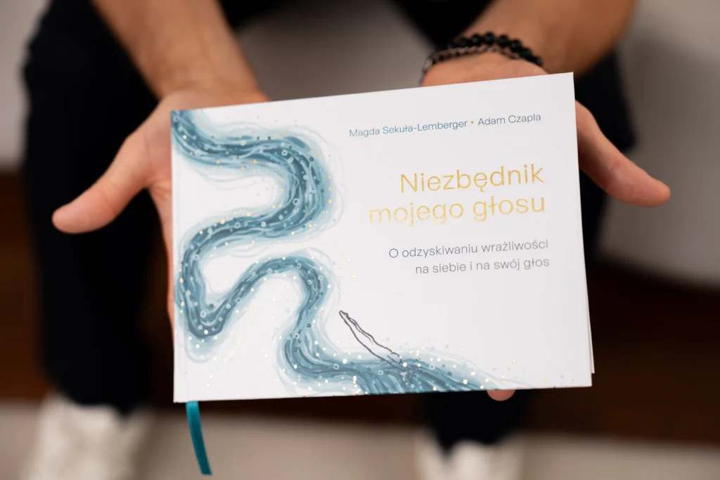 Ręce trzymające książkę "Niezbędnik mojego głosu".